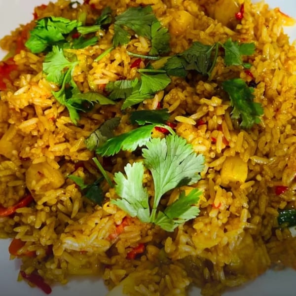Close-up of golden Thai pineapple fried rice with red peppers and fresh cilantro.