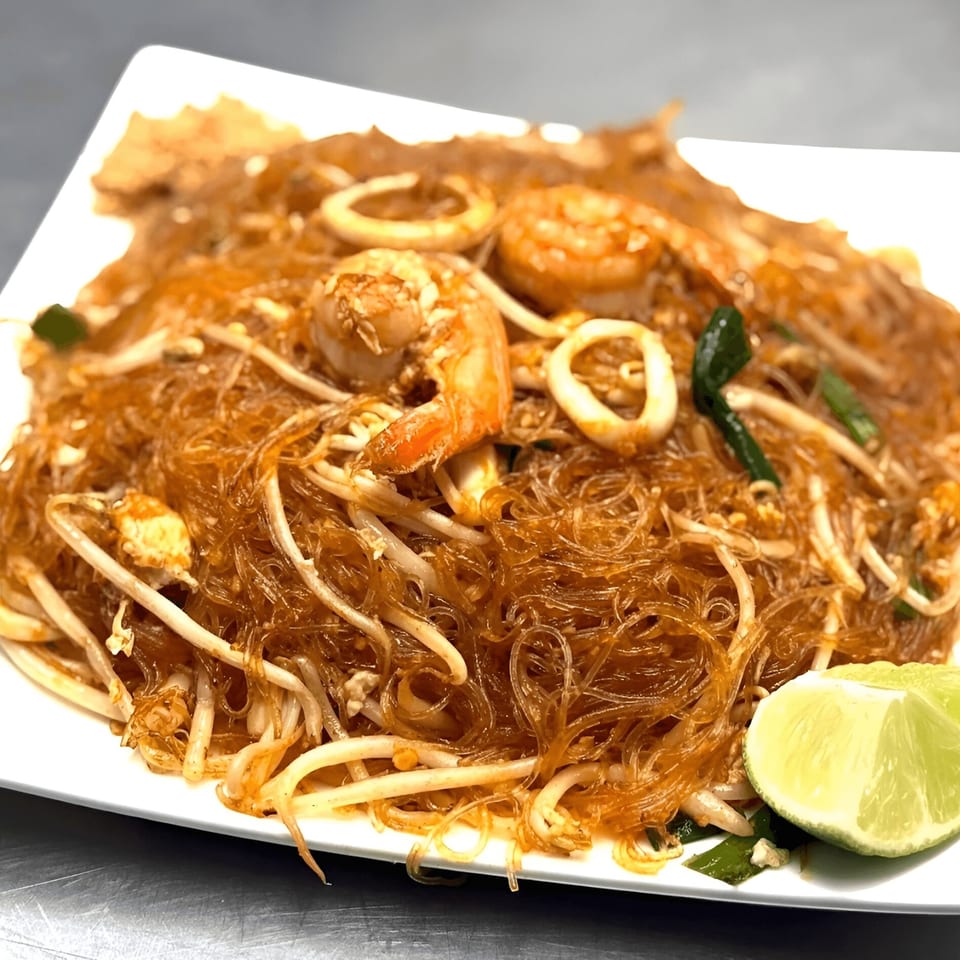 Omaha Mercy Thai's Pad Woon Sen with shrimp, squid, bean sprouts, and lime on a white plate.